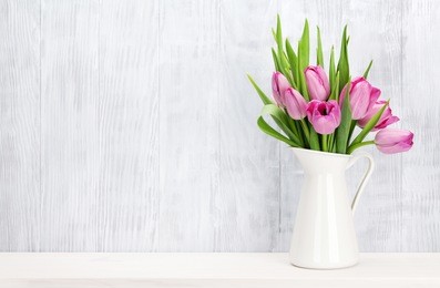 fresh pink tulip flowers bouquet on shelf in front of wooden wall. view with copy space