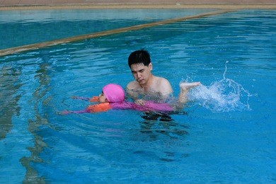 asian father teaching his daughter to swim
