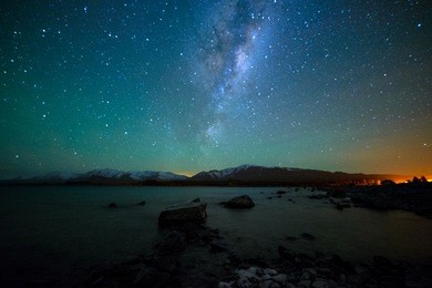 milky way rising above lake tekapo, new zealand with aurora australis or the southern light lighting up the sky . noise due to high iso; soft focus / shallow dof due to wide aperture used.