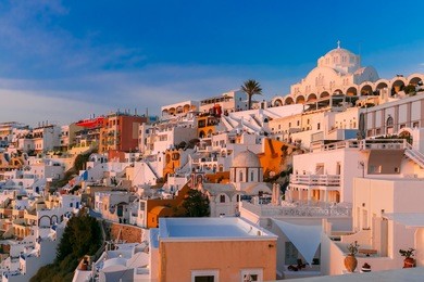 fira, main town of the island santorini, sea, white houses and church at sunset, greece
