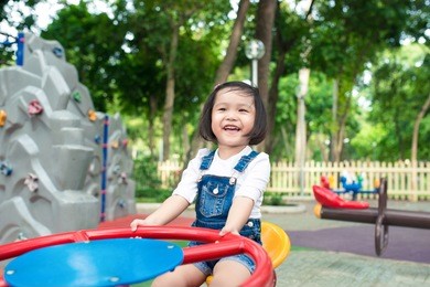asian baby girl playing on a swing and having fun in park