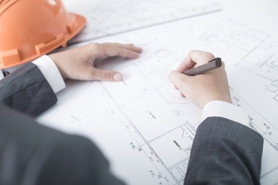 closeup cropped image of a young male architect working on blueprints spread out on a table