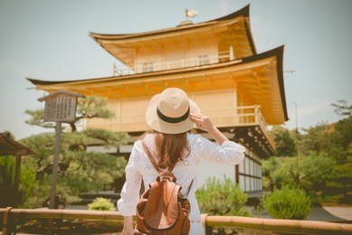 lady tourist is watching kinkaku-ji temple in kyoto, japan