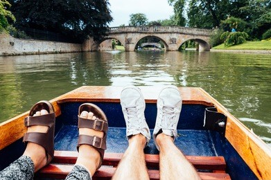 man and woman feet on a boat punting in the river in  cambridge. focus on feet.