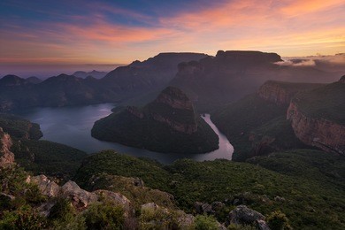 the sun paints high clouds in oranges over the blyde river canyon at sunrise