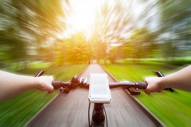 riding a bike first person perspective. smartphone attached to handlebar. speed motion blur. countryside road towards sun.