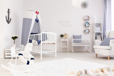 spacious baby room with simple white furniture and beautiful marine decorations