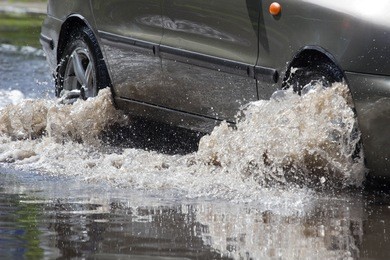 cars driving on a flooded road during a flood caused by heavy rain,