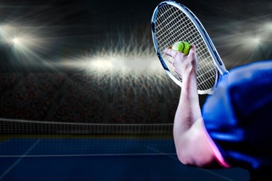 tennis player holding a racquet ready to serve against digitally generated image of blue tennis court illuminate by spotlight