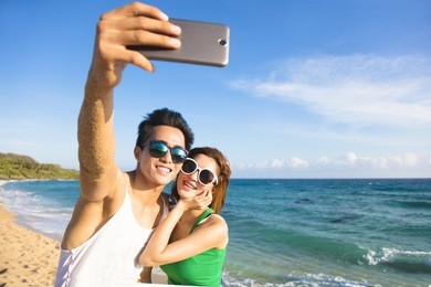 young couple  taking vacation selfie photograph at the beach

