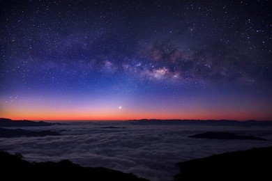 milky way on night sky over foggy mountain