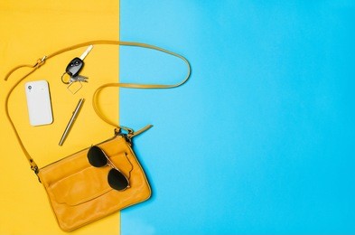 woman's accessories lying flat on textured fabric background. blue and yellow pastel colors with copy space around products. horizontal image or photograph.