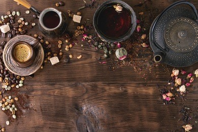 food background tea and coffee theme. different black and green dry tea, different coffee beans, cup of hot tea and coffee,  teapot over dark wooden background. top view. space for text
