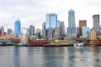 seattle ferris wheel, waterfront and skyline on a bright sunny day with blue sky and clouds. view is from the water