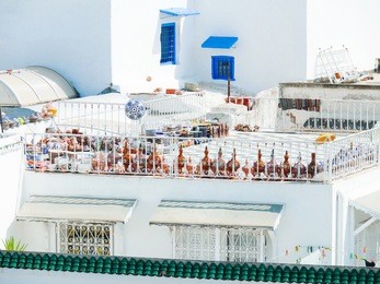 traditional white and blue exterior of house in sidi bou said, tunisia. colorful pitchers on roof top.