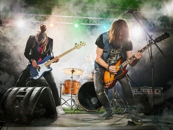 rock band performs on stage. guitarist, bass guitar and drums. the guitarist plays solo.