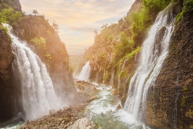 waterfall in mountain forest under great sky.