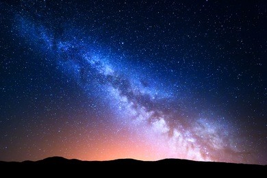 night landscape with colorful milky way and yellow light at mountains. starry sky with hills at summer. beautiful universe. space background