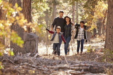 happy hispanic family with two children walking in a forest