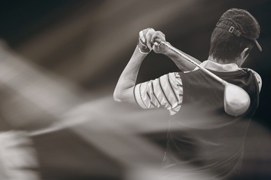 man playing golf against black background
