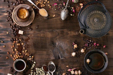 food background tea and coffee theme. different black and green dry tea, different coffee beans, cup of hot tea and coffee,  teapot over dark wooden background. top view. space for text