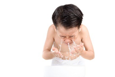 young boy wash his face by fresh water in white bathroom.