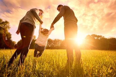 happy family in the park evening light. the lights of a sun. mom, dad and baby happy walk at sunset. the concept of a happy family.parents hold the baby's hands.