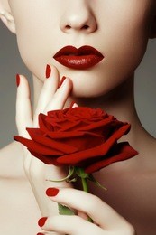 beauty fashion model woman face. portrait with red rose flower. red lips and nails. beautifu woman with luxury makeup and manicure