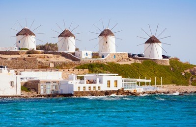 the famous windmills of mykonos island surrounded by sea.