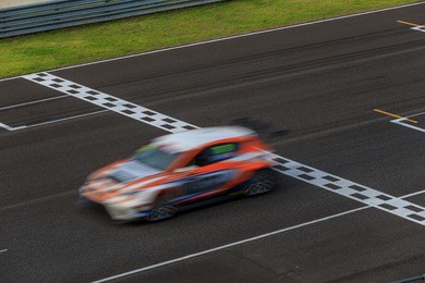 race car racing on speed track with motion blur, crossing finish line 
