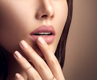 beauty fashion woman lips with natural makeup and beige nail polish. matte lipstick and nails. beauty girl face close up. nude colors. sexy lips, manicure, make up