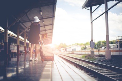 traveler girl walking and waits train on railway platform.