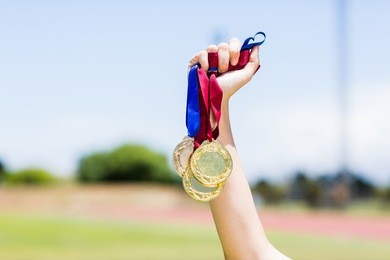 hand of female athlete holding gold medal in stadium