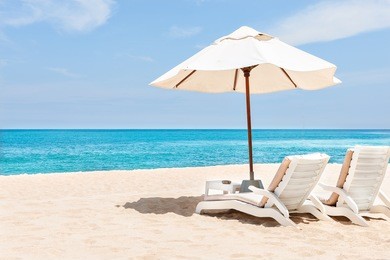sea chairs and umbrellas on the sand near blue water side with horizon and clear sky