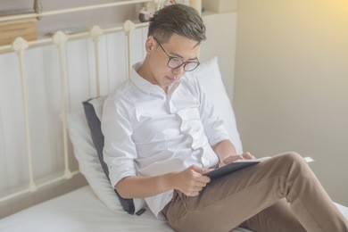serious young businessman sitting in bed reading book