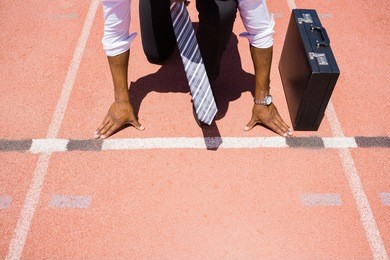 businessman with briefcase ready to run on running track