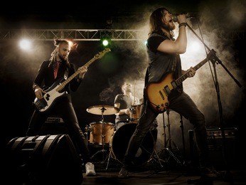rock band performs on stage. guitarist, bass guitar and drums. the guitarist plays solo.