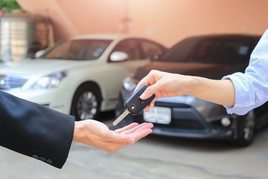 female hand giving a key for buyer or rental car.