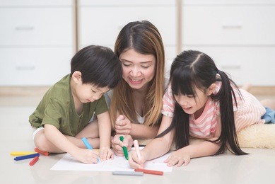 asian family drawing picture with crayons