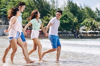 somebody taking photo of friends jumping at the beach