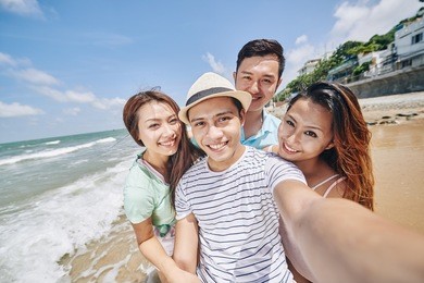 somebody taking photo of friends jumping at the beach