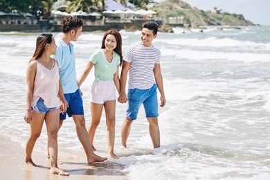 somebody taking photo of friends jumping at the beach