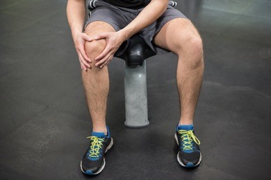 close-up of man with an injured knee sitting in gym