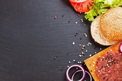 the raw ingredients for the homemade burger on black slate background. top view.