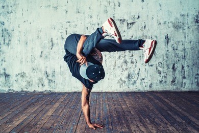 young man break dancing on wall background
