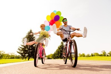 happy funny young couple riding on bicycle with raised legs