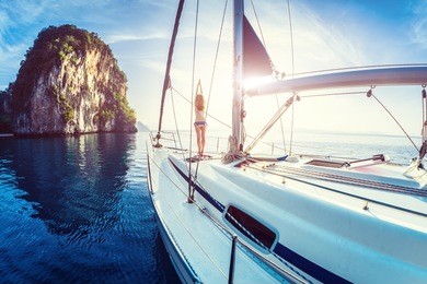 young lady standing on the bow of yacht and doing exercise at sunrise
