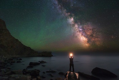 man and universe, shore of the ocean, sea, fire and stars in hands, in palms, igniting stars, inspiration photo, unity the man and universe, astronomy and astrophotography, milky way, green airglow