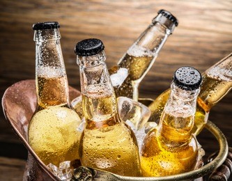 cold bottles of beer in the brazen bucket on the wooden table.