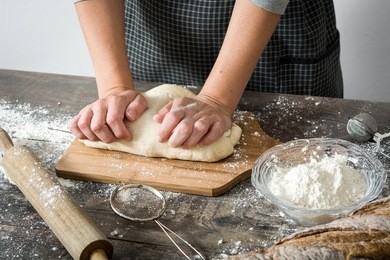 woman making bread with her hand on rustic wood

